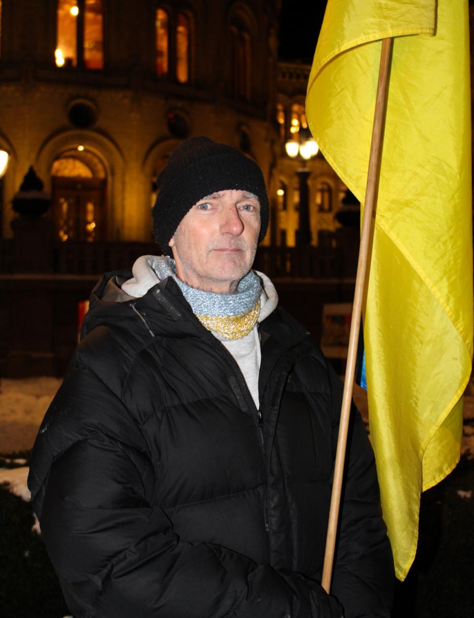 Morten Besshø poserer foran Stortinget med et Ukrainsk flagg