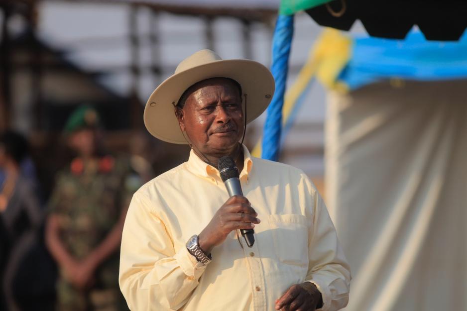 President i Uganda Yoweri Museveni står med en mikrofon i hånden. Han har på solhatt. 