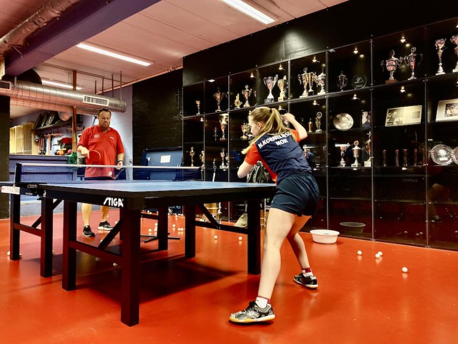 Nora Korneliussen slår ballen i bordtennis mot landslagstreneren sin, Jan Bergersen.