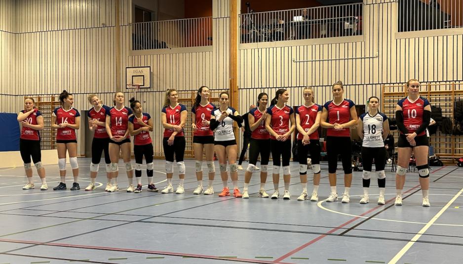 Et volleyball lag som står på rekke i en gymsal