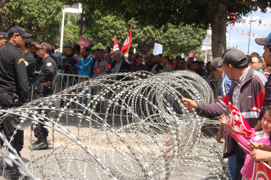 Noen folk som står bak en piggtråd i Tunisia