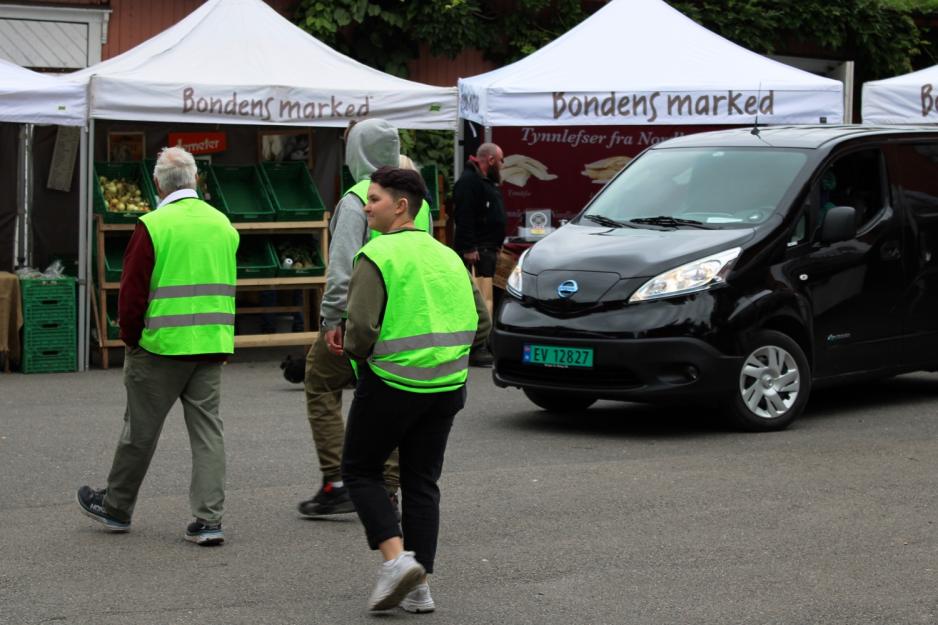 Tre ansatte ved Bondens marked er fotografert foran en svart varebil.