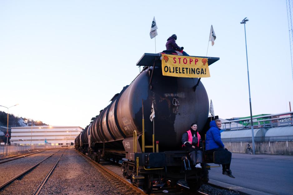 Aksjonister fra Extinction Rebellion sitter foran og oppå tankvogner fylt med flybensin.