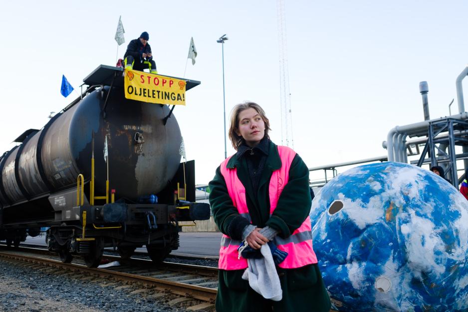 Emilie Røine Østebø står foran en blokkert tankvogn spent opp med banner fra Extinction Rebellion.