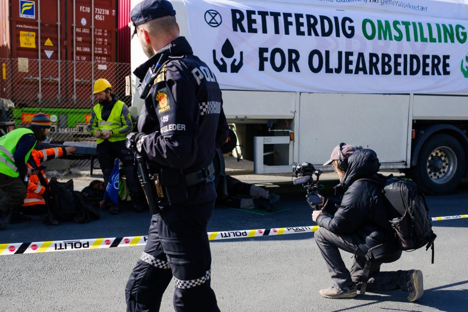 Thomas Østbye filmer aksjonistene mens en politimann går forbi.