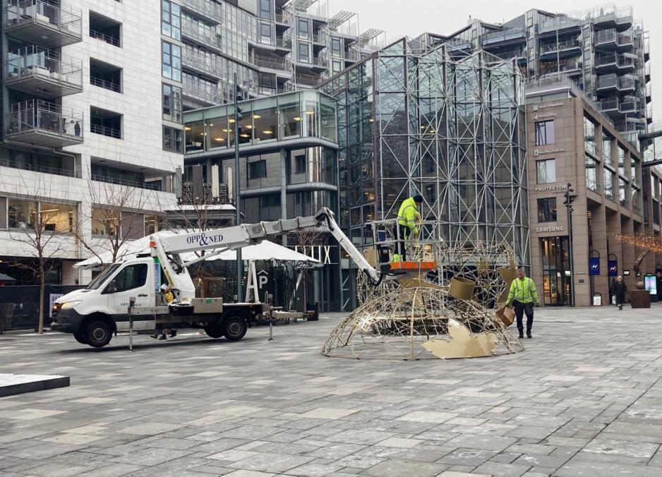 Den digre gule julekulen midt på torget rives ned av to menn i neongrønne jakker. 