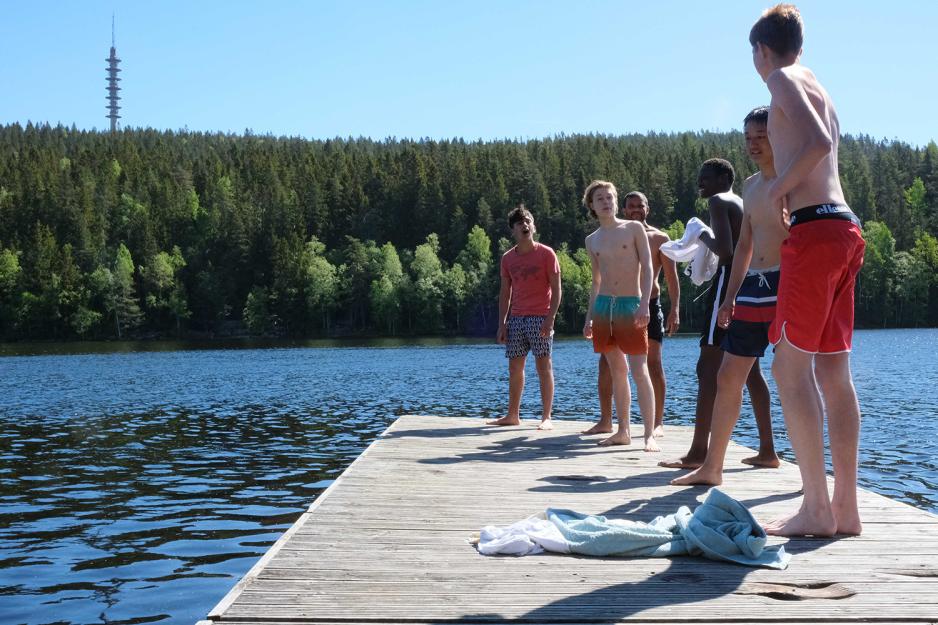 En guttegjeng står på flytebrygga og ser klare ut til å hoppe i vannet. 