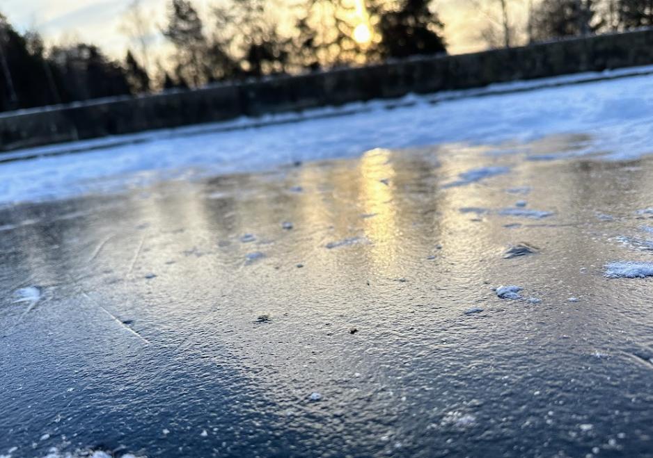 En mørk is på Vesletjern med svak sol i bakgrunnen. 