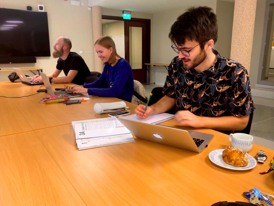 Tre studentar sit ved eit bord og arbeidar.