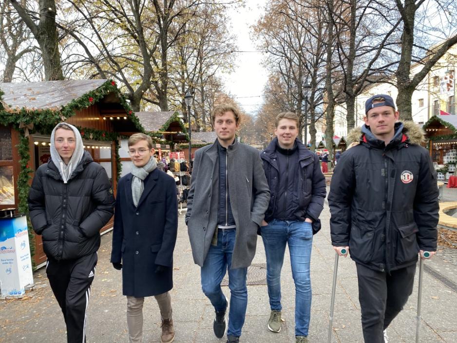 Fem gutter i tidlig 20-årene går på linje mot kamera. 