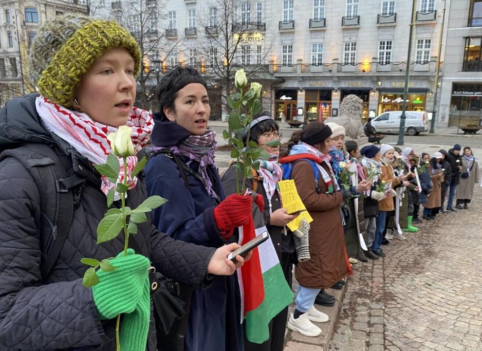 Demonstrander som synger med roser i hendene foran stortinget