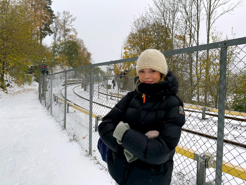 Jente står og venter på T-banen på Gråkammen stasjon. Det snør.