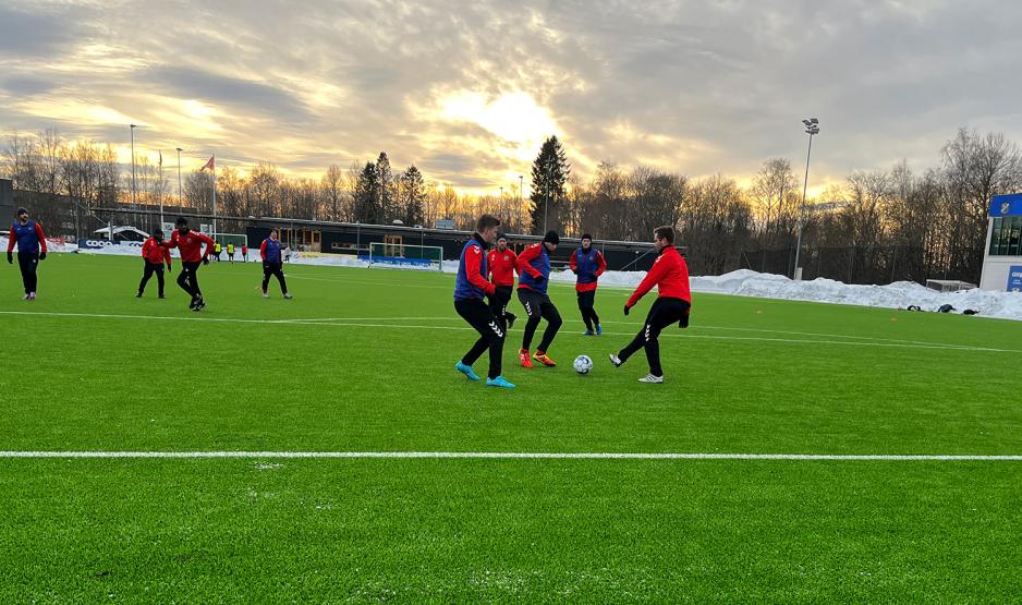 Fotballspillere som spiller treningskamp under solnedgang