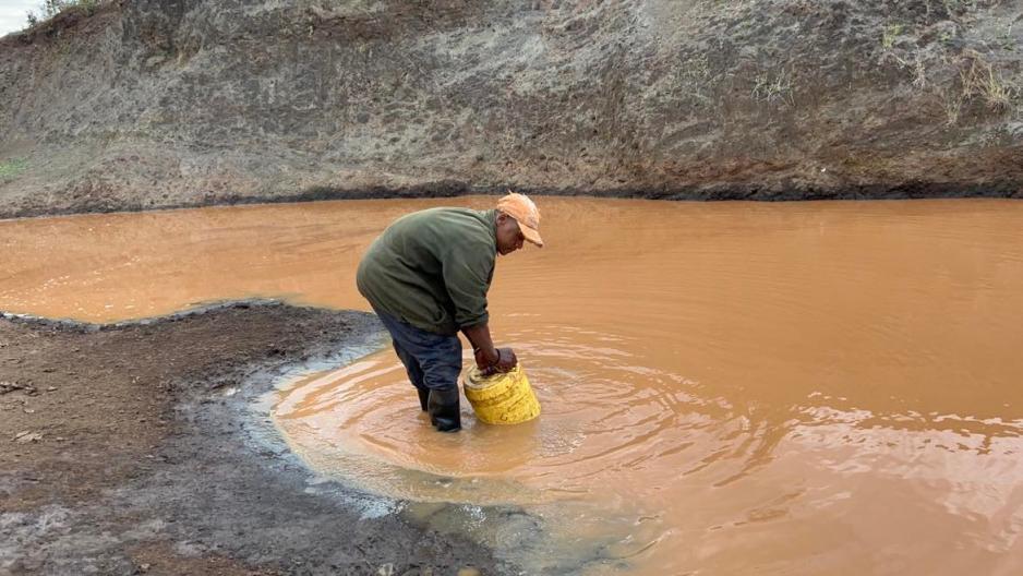 Bilde av en mann i Afrika som samler skittent vann i en gul plastdunk