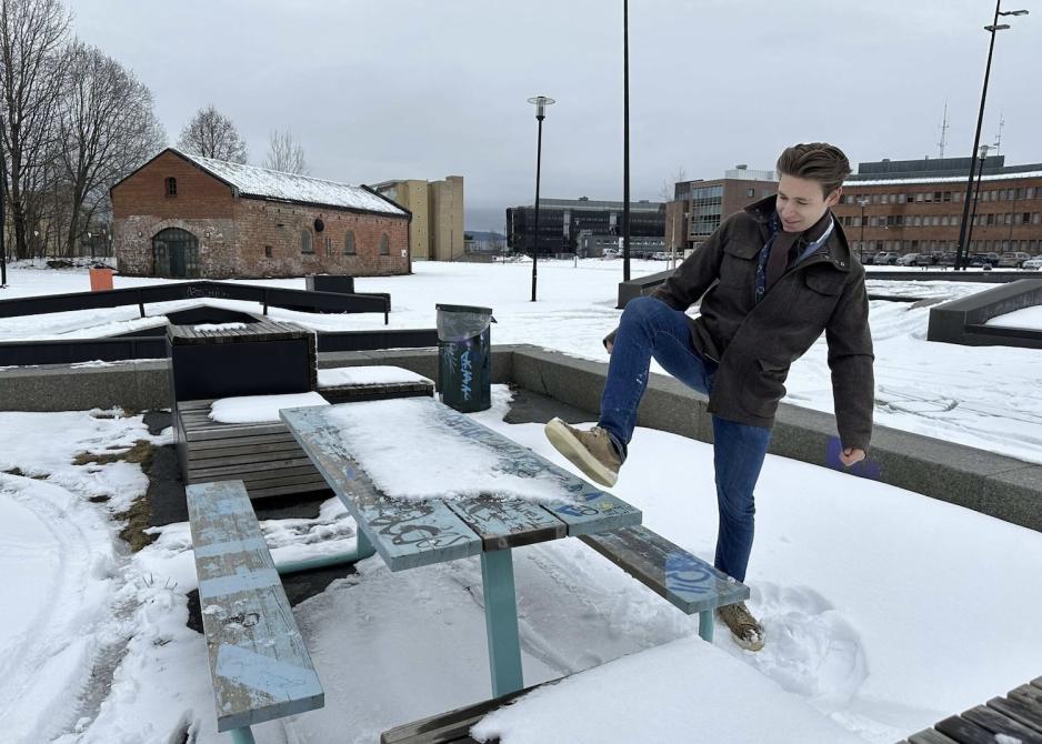 En ung gutt som sparker vekk snøen fra en benk