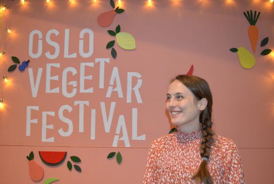 Ung kvinne står foran Oslo Vegetarfestival-skilt og smiler