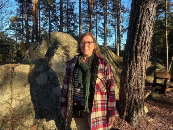 Helga Gunnarsdóttir, styreleder i Østmarkas venner står i sollyset i skogen