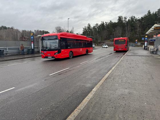 Det er to røde ruter-busser på holdeplassen.