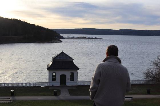 Arild Berg står på toppen av en bakke, nedenfor er det et hus.