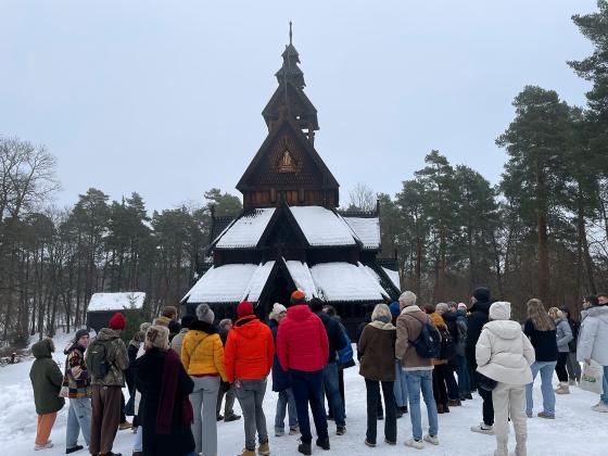 En stavkirke med en mengde mennesker rundt. De er på omvisning.