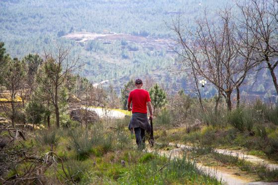 En mann går i fjellet. Et dagbrudd kan ses i fjellet i bakgrunnen.