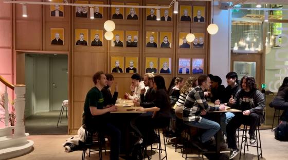 Mennesker sitter rundt langbord og snakker