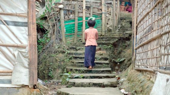 En ung jente går oppover en trapp i en flyktningeleir i Bangladesh
