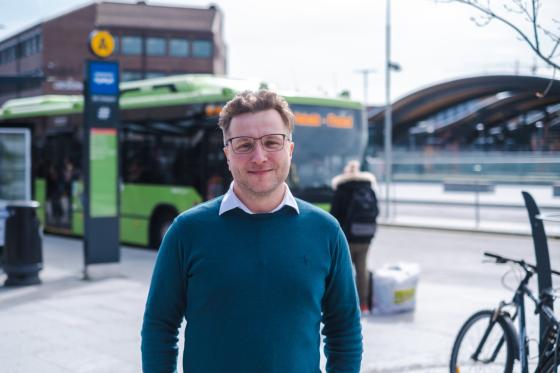 Adrian Pracon står foran en buss