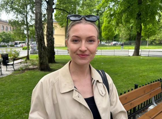 Ung dame som smiler til kamera mens hun venter på bussen.