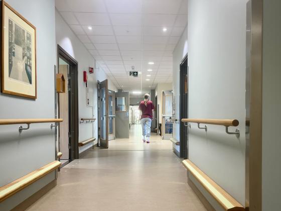Sykepleier går nedover gangen på et sykehjem