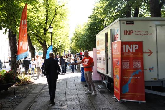 Mann fra INP rekker ut en valgbrosjyre til en forbipasserende mann