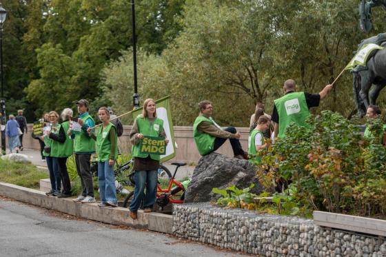 En gruppe MDG representanter står på siden av veien og reklamerer for Miljøpartiet de Grønne