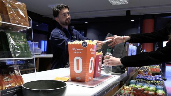 Mann selger popcorn til kunde. På kino. 