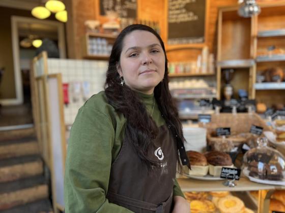 Bilde av assisterende leder Inga Staugaite på Åpent Bakeri, foran disken i bakeriet.