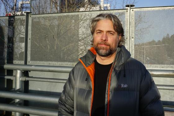 Mann står i direkte sollys med et alvorlig ansiktsuttrykk.