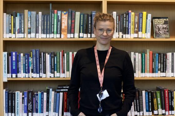 Frid Hamsun står foran en bokhylle. Hun er seksjonsleder på Deichman Lambertseter