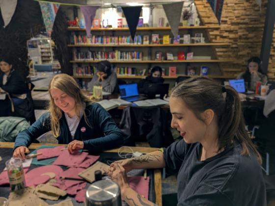 Celine Lyngås Sataøen og Elisa Halvorsen Castillo sitter ved et bord på Deichman Stovner og lager papir