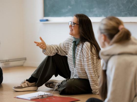 Martine Tufvesson  Lundberg sitter p&aring; gulvet i et klasserom sammen med elever