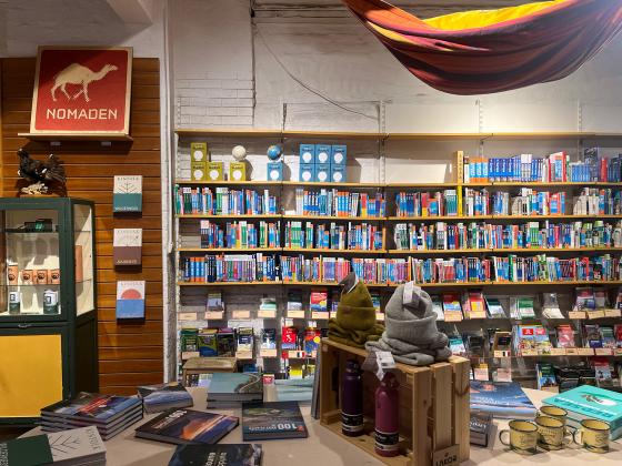 Innsiden av butikken Nomaden. Bokhyller, utstilling med turkl&aelig;r og butikkens skilt. 