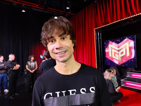 R&oslash;d gardin. Mann foran. Smiler. Sort genser.