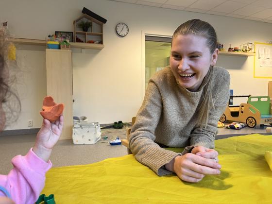Karoline Utvik sitter &aring; leker med plastelina med barna i barnehagen.