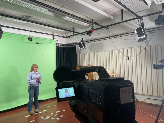 Kvinne foran greenscreen med kamera siktet p&aring;