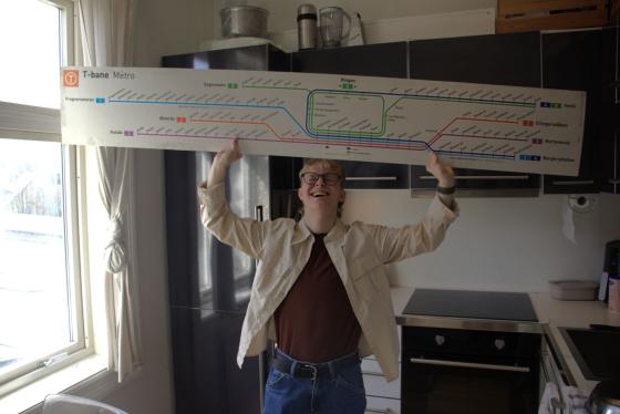 Mann holder opp skilt med alle t-banelinjene