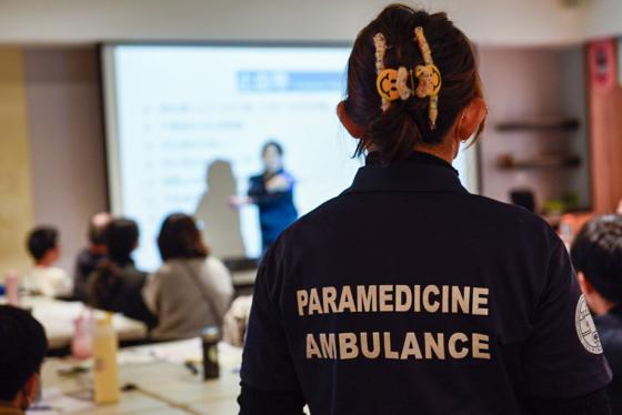 En ambulansemedarbeider st&aring;r i et klasserom.