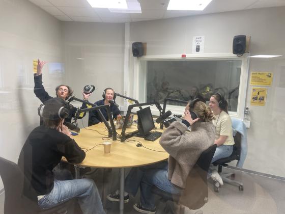 to programledere og tre gjester i radiostudioet