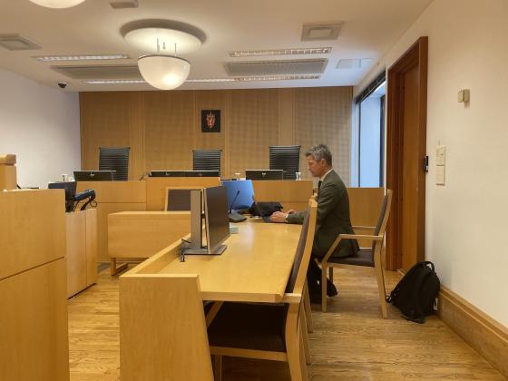 En advokat i en rettssal, sitter ned bak pc-skjermen