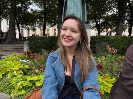 Kitty Gjerland sitter foran en statue. Hun smiler. 