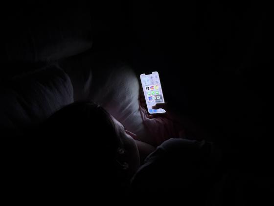 Jente ser p&aring; mobiltelefonen fylt med sosiale medier.