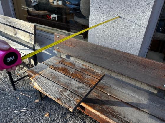 Et målebånd viser en meter fra veggen. under er det et kafébord.