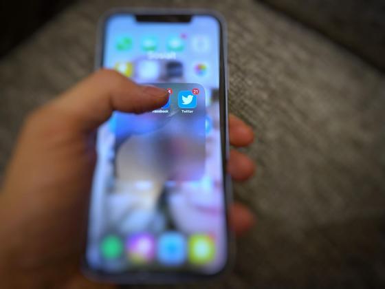 En hånd som holder en telefon med bilde av Twitter applikasjonen 